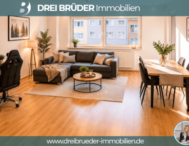 Ein helles und modernes Wohnzimmer mit einem grauen Sofa, einem runden Tisch und einem Esstisch. Pflanzen und Bilder an den Wänden ergänzen die gemütliche Atmosphäre. Ein Schreibtisch mit Computer steht ebenfalls im Raum und große Fenster sorgen für genügend Tageslicht.