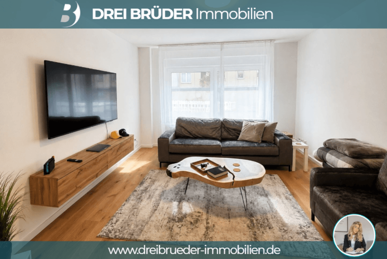 Ein modernes Wohnzimmer mit zwei grauen Sofas, einem Couchtisch aus Holz und einem kraftvollen Fernseher an der Wand. Helle Wände und viel Tageslicht durch große Fenster schaffen eine einladende Atmosphäre. Ein Teppich ergänzt das gemütliche Ambiente.