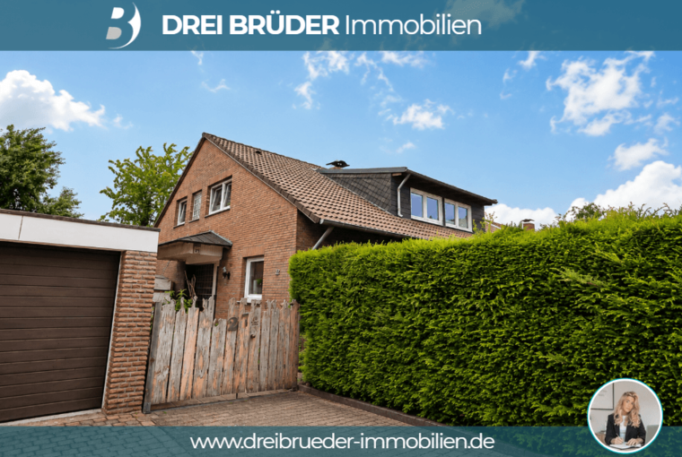 Ein zweigeschossiges, braunes Wohnhaus mit einem Satteldach und Fenster im Dachgeschoss. Der Eingangsbereich ist gut sichtbar, umgeben von einem gepflegten Garten und einer hohen Hecke. An der Seite ist eine Garage. Der Himmel ist blau mit einigen Wolken.