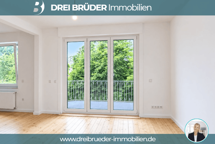 Ein heller, leerer Raum mit Holzfußboden und großen Fenstern, die auf einen Balkon mit Blick ins Grüne führen. Die Wände sind weiß und der Raum wirkt freundlich und einladend.